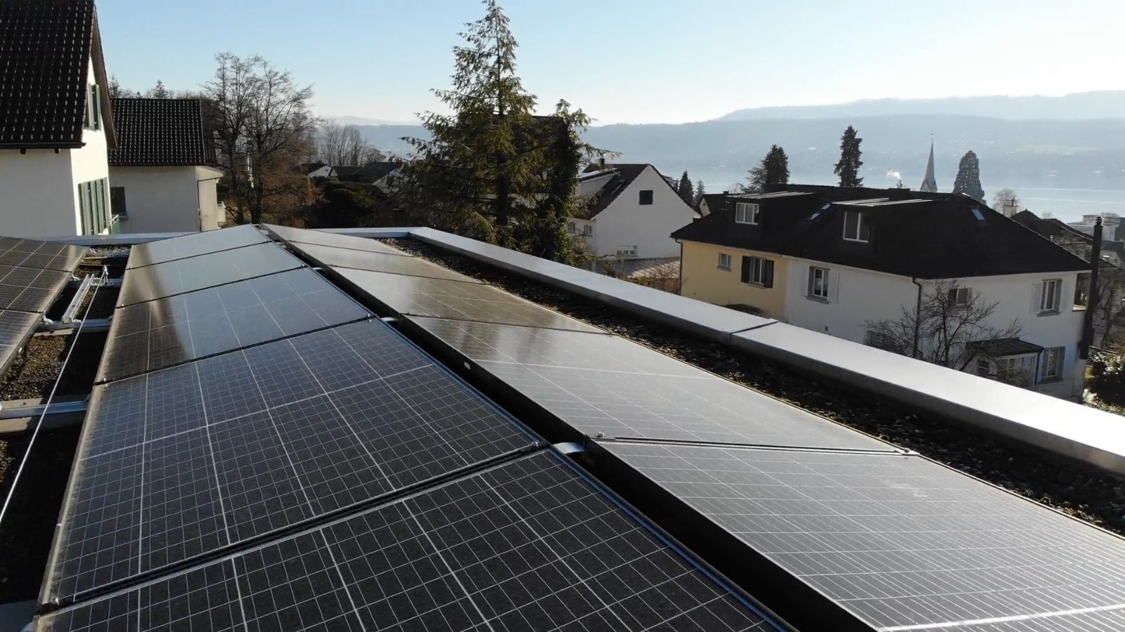 Rows of solar panels on a flat residential roof above neighbouring houses