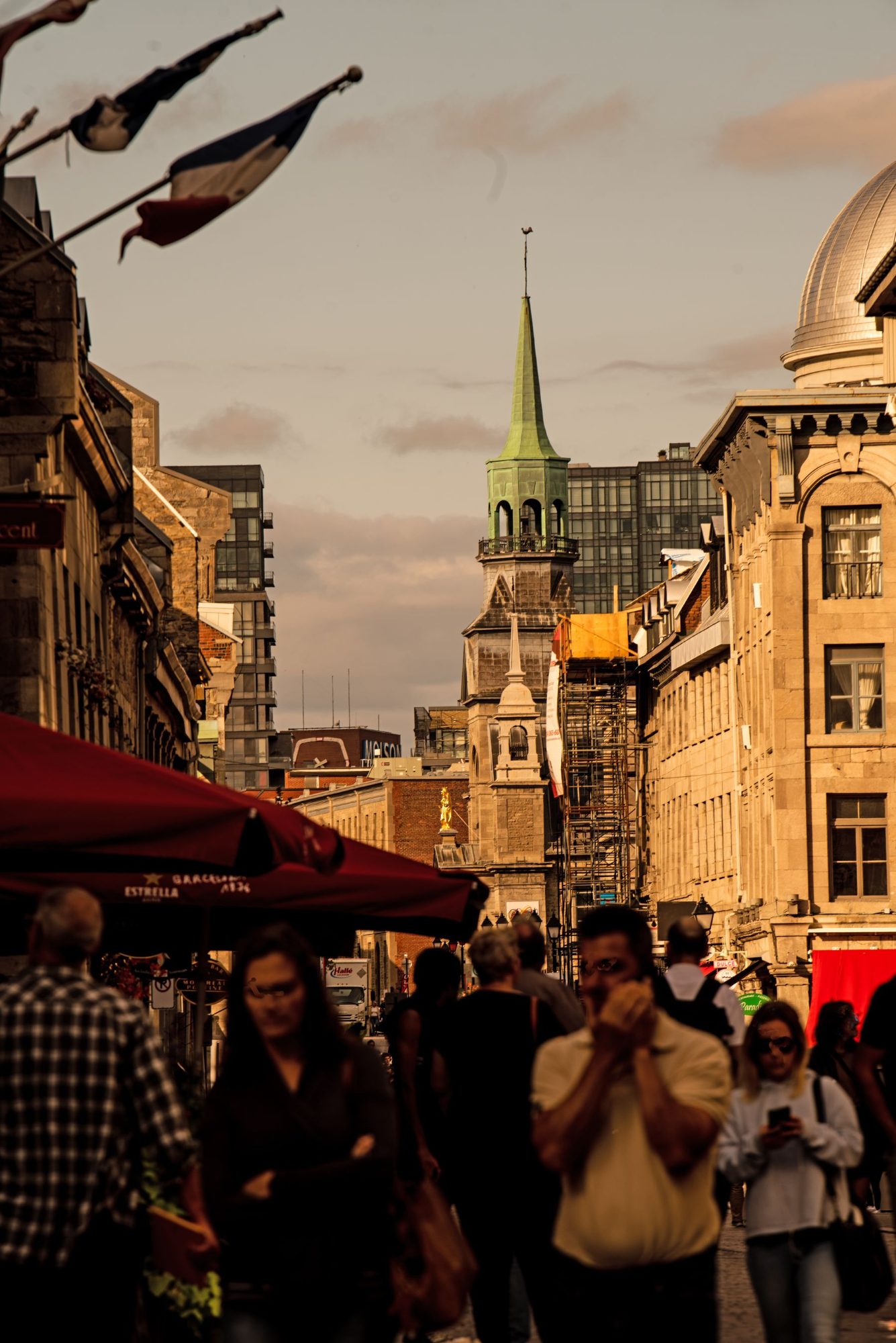 Evening crowd on a street in Old Montréal beneath a copper church spire